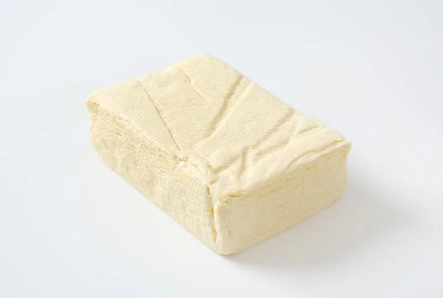Kus bílého tofu na neutrálním pozadí.