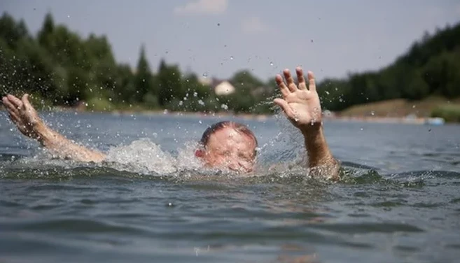 Muž tonoucí v jezeře s rukama zvednutýma k nebi.