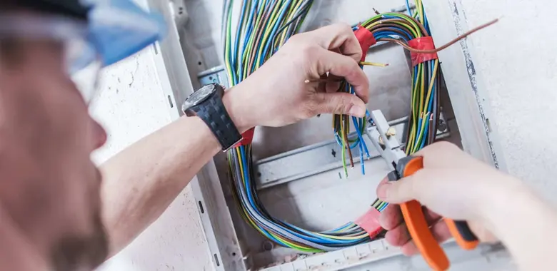 Elektroinženýr připojuje vodiče v rozvaděči pro domácí instalaci.