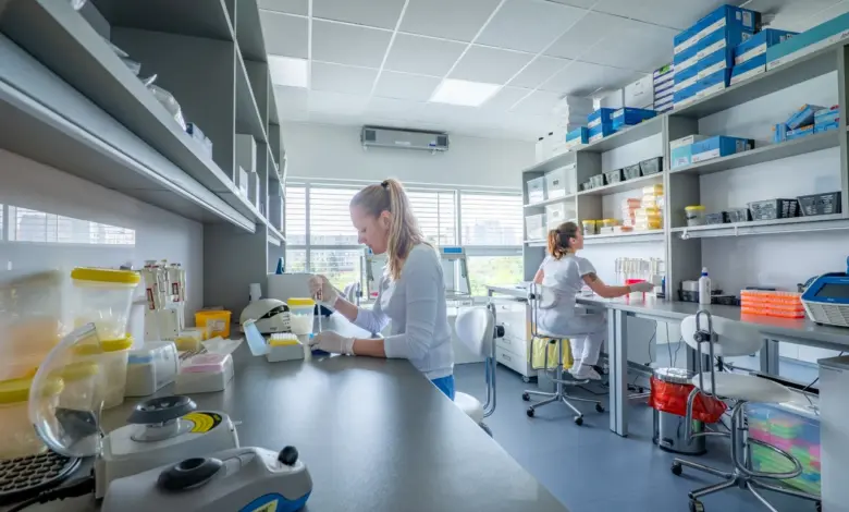 Dvě vědkyně pracují v laboratoři s mikroskopem a vybavením.