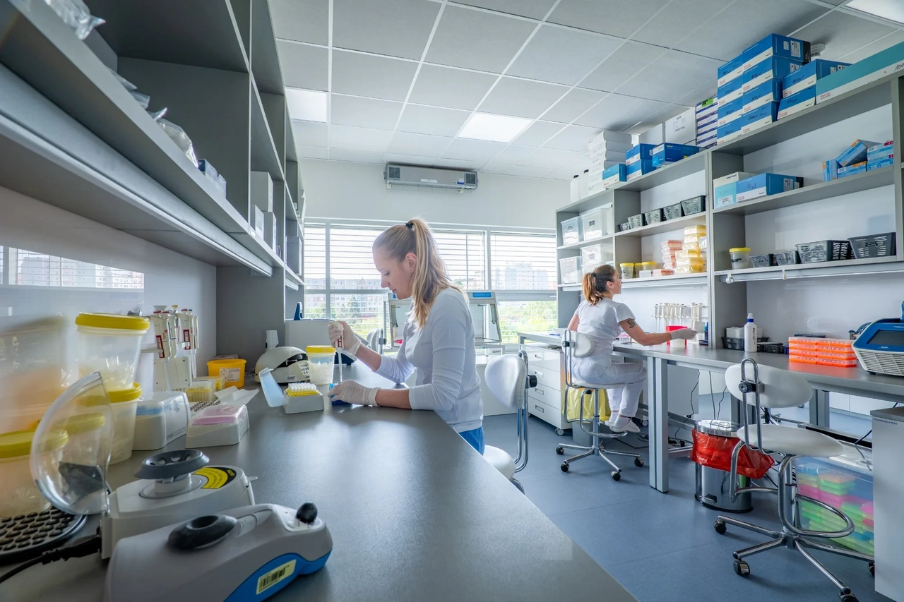 Dvě vědkyně pracují v laboratoři s mikroskopem a vybavením.