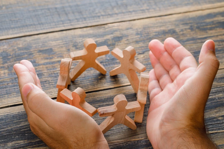 Hands holding wooden figures in circle