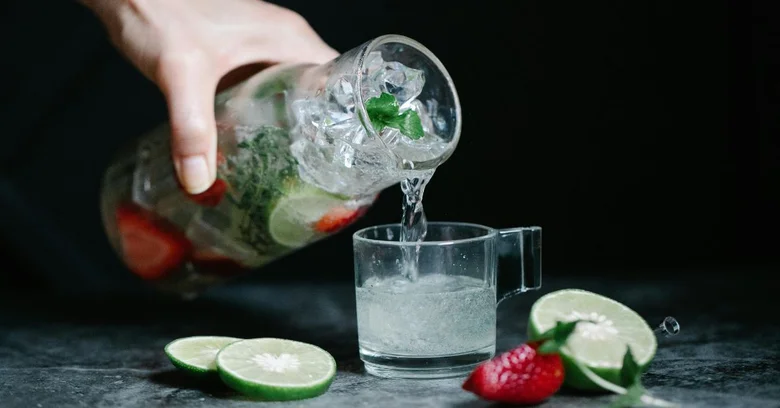 Lidé nalévají osvěžující nealko drink s ovocem do sklenice.