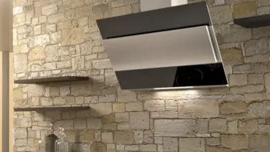 Moderní digestoř nad varnou deskou v kuchyni s kamenným obkladem.