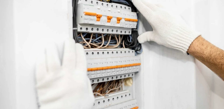 Elektroinženýr montuje jistič do rozvaděče s viditelnými kabely.