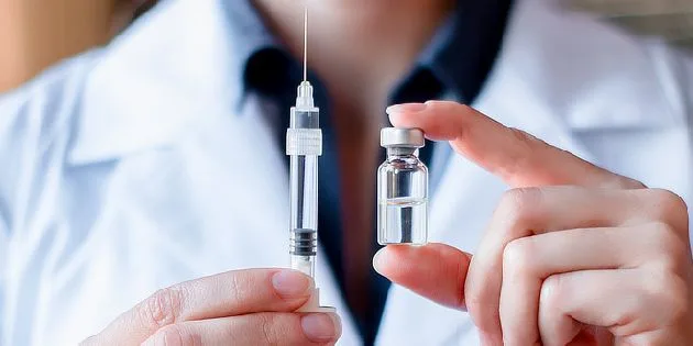 Zdravotník drží lahvičku vakcíny a stříkačku