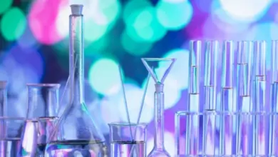 Laboratorní sklo s tekutinami na barevném pozadí.