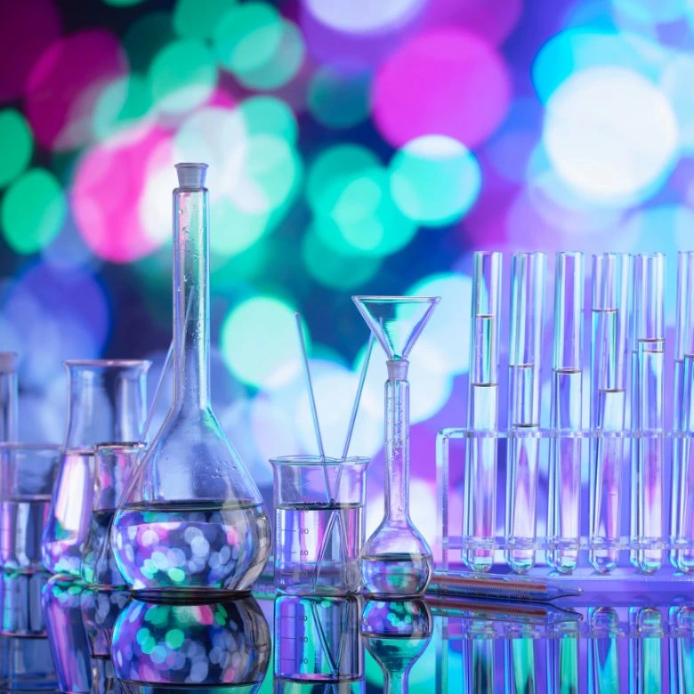 Laboratorní sklo s tekutinami na barevném pozadí.