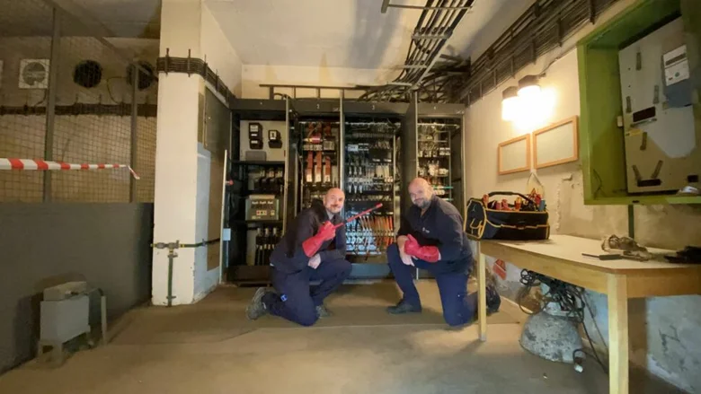 Električtí pracovníci kontrolují rozvaděč v technické místnosti.