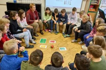 Děti sedí v kruhu ve třídě pro podporu sociální interakce.