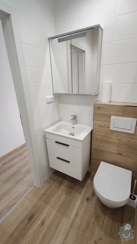 Moderní koupelna s bílými dlaždicemi a dřevěnou podlahou pro inspiraci při rekonstrukci bytu.