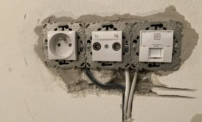 Instalace elektrických zásuvek s viditelným vedením v zdi.