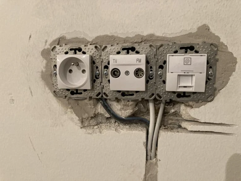 Instalace elektrických zásuvek s viditelným vedením v zdi.