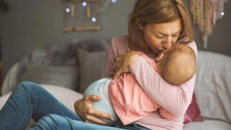 Žena krmit novorozence na posteli v domácnosti.