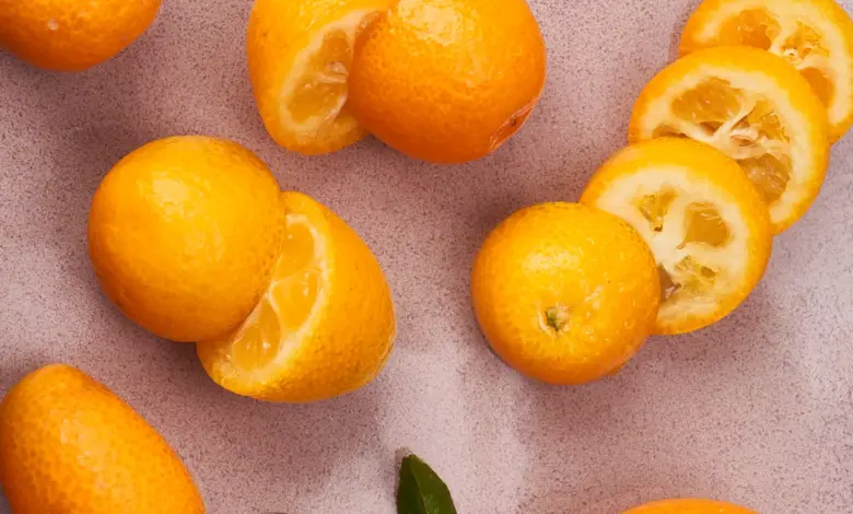 Čerstvé pomeranče a nakrájené citrusy na texturovaném povrchu